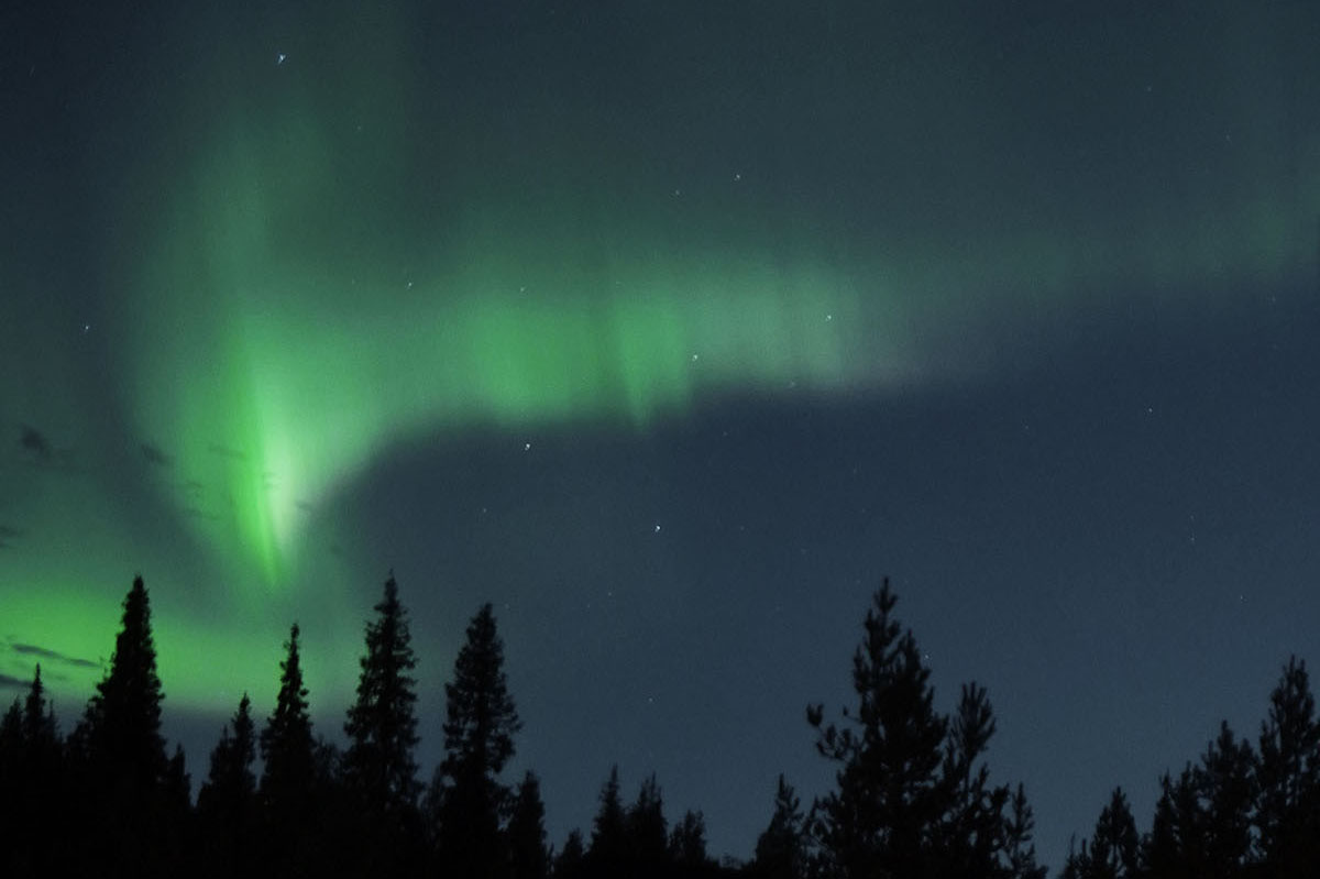 The Aurora Borealis above a glass-roofed cabin at Northern Lights Village Levi in Finnish Lapland | These Four Walls blog